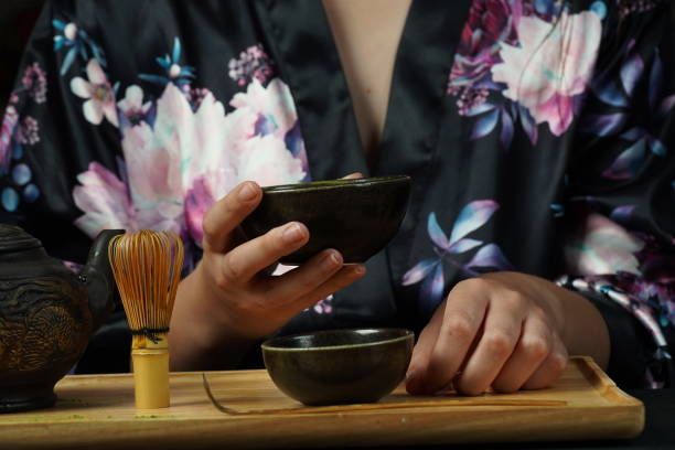 istock Woman tea master in kimono performs tea ceremony. Matcha green tea powder with a bamboo whisk and scoop as used in a traditional Japanese tea ceremony. 1491639311