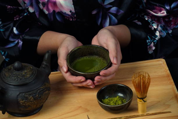 istock Woman tea master in kimono performs tea ceremony. Matcha green tea powder with a bamboo whisk and scoop as used in a traditional Japanese tea ceremony. 1491639312
