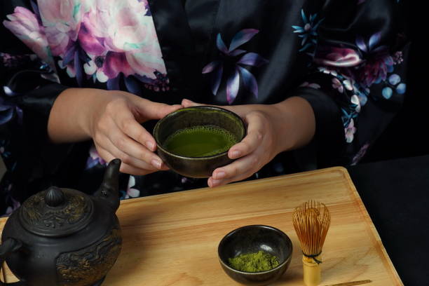 istock Woman tea master in kimono performs tea ceremony. Matcha green tea powder with a bamboo whisk and scoop as used in a traditional Japanese tea ceremony. 1491639313
