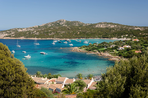Indulge in the breathtaking beauty of Sardinia's picturesque seacoast captured in this stunning iStock photo. The scene unfolds like a masterpiece of nature, with a wide-angle view that invites you to immerse yourself in its splendor.\n\nIn the foreground, lush green vegetation creates a vibrant frame, adding depth and a sense of tranquility to the composition. The crystal-clear blue waters of the Mediterranean glisten under the warm sunlight, inviting you to embark on an adventure or simply bask in the serenity of the moment.\n\nLuxury yachts and boats gracefully navigate the coastal waters, adding a touch of elegance and sophistication to the scene. Their presence hints at the allure and opulence that Sardinia's coastal regions have to offer, from exclusive marinas to hidden coves waiting to be explored.\n\nAs your gaze extends towards the horizon, rolling hills emerge, seemingly painted in shades of green, dotted with charming villas and rustic buildings. They create a harmonious backdrop, seamlessly blending the allure of nature with the timeless charm of human habitation.\n\nIn this captivating coastal symphony, Sardinia's seacoast presents a captivating blend of natural beauty, coastal luxury, and Mediterranean charm. It beckons you to escape the ordinary and immerse yourself in a world where land and sea merge in a breathtaking display of serenity and splendor.