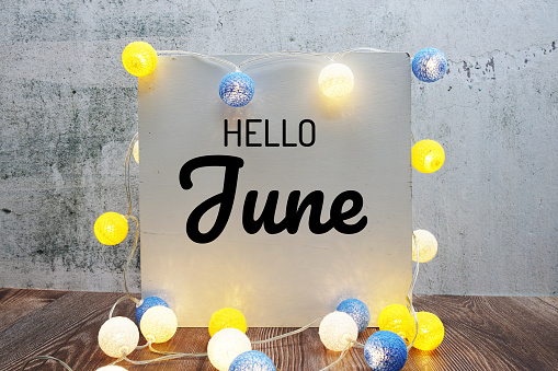 Hello June text message with LED cotton ball decoration on wooden background