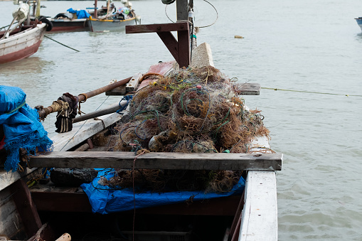 Pile of fishing nets and seaweed on a boat on a pier