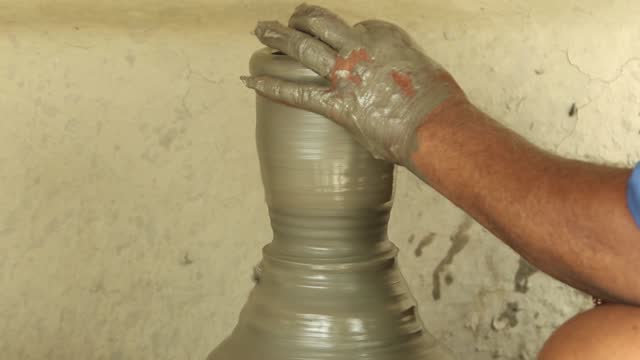 potter's hands working on pottery wheel and making a pot.