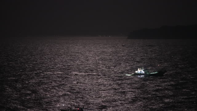 Fishing boats sailing on the midnight sea illuminated by the moonlight of the full moon, Katsuura