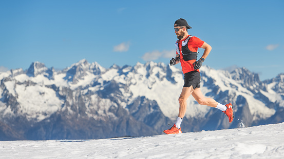 Trail running athlete runs in the snow at high altitude