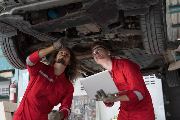 grupa mężczyzn mechanik samochodowy naprawia oś samochodową, zawieszenie i hamulec tarczowy w warsztacie samochodowym. zespół techników sprawdzających przekładnię redukcyjną osi pod podnośnikiem w warsztacie garażowym - trainee auto repair shop computer manual worker zdjęcia i obrazy z banku zdjęć