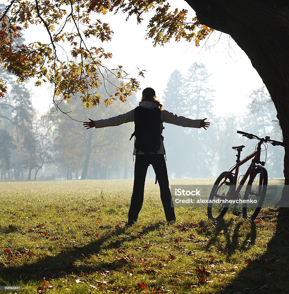 Cycliste enthousiaste femme debout dans un parc avec mains écartés - Photo de Activité libre de droits