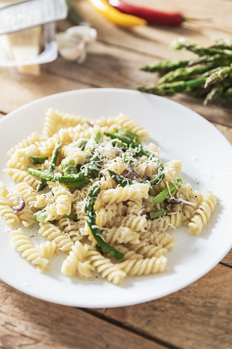 Simple pasta meal, fusilli with asparagus and hard cheese on plate, close-up