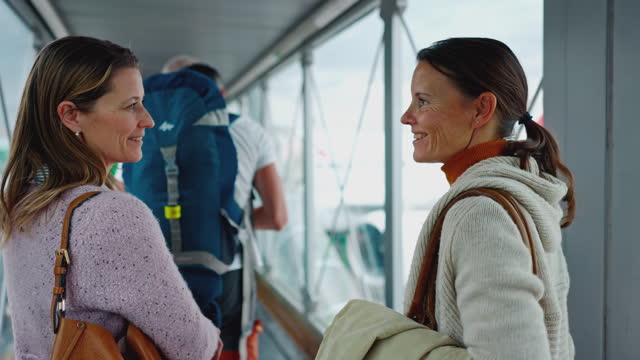 WS Two women waits in the line inside of a sky bridge while boarding a plane