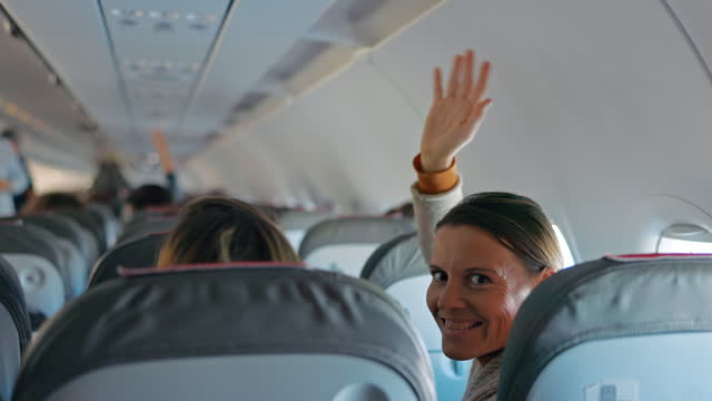LS Two female passengers looking and waving at the camera inside of the plane