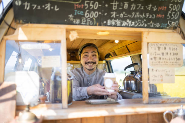 istock Service with a smile - a man serving coffee from his mobile coffee van 1491675134