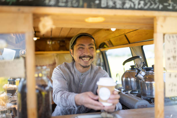 istock Service with a smile - a man serving coffee from his mobile coffee van 1491675139