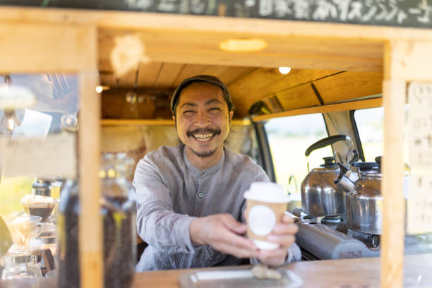 istock Service with a smile - a man serving coffee from his mobile coffee van 1491675295