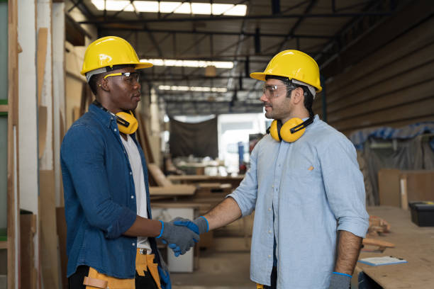 portrait of two male carpenter successful of work and shaking hands together in wood workshop. group of male joiner finished of work in furniture workshop - manual worker handshake industry warehouse imagens e fotografias de stock