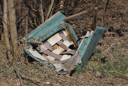 one old broken white green chair made of fabric and wooden boards lies on the ground and grass on the street