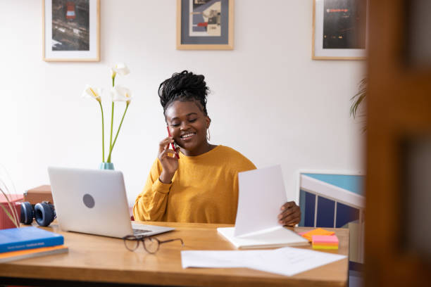 istock Young African American woman talking on her smart phone and working at home 1491677607