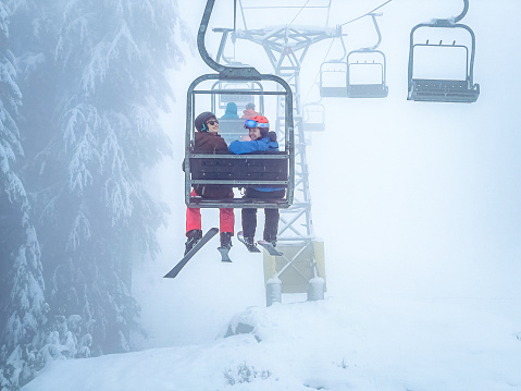 Young Multiracial Skiers Smiling on Ski Lift, Misty Day