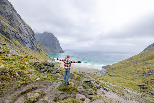 Young man hiking in a beautiful scenery in Norway.\nLofoten islands, Norway