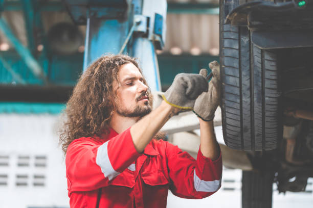 istock Auto mechanic working in garage, Technician man working in auto service with lifted vehicle, Car repair and maintenance 1491680704