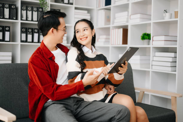 istock Two asian students learning together online with a laptop, tablet and tutor together in liveing room at home. 1491680752