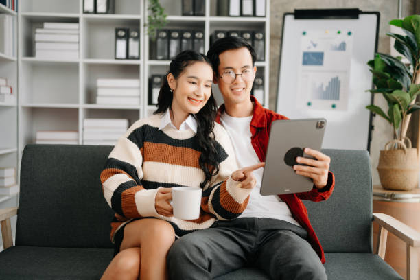 istock Two asian students learning together online with a laptop, tablet and tutor together in liveing room at home. 1491680762
