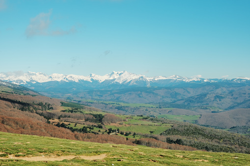 views of the Pyrenees mountain range. Basque Country Zone. views to the Pyrenean mountain range. Basque Country area. Spring. Green valleys and trees still bare. Snowy mountain peaks. Wide angle view.