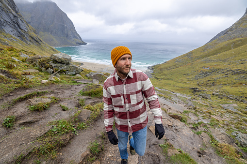 Young man hiking in a beautiful scenery in Norway.\nLofoten islands, Norway