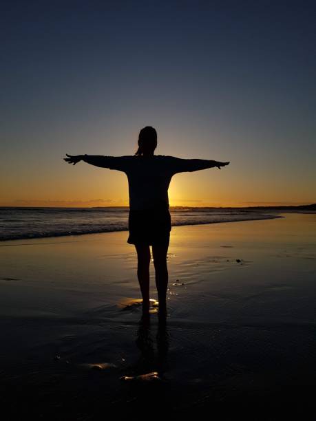istock woman silhouette at sunset on the beach 1491686579