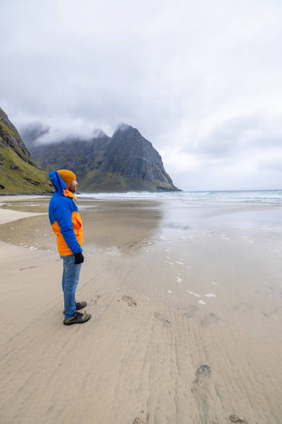 istock Distant man standing on an empty beach in Norway, he looks at the ocean 1491688258