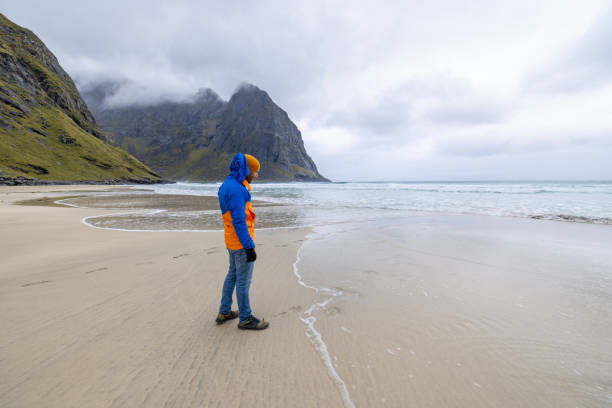 istock Distant man standing on an empty beach in Norway, he looks at the ocean 1491688692