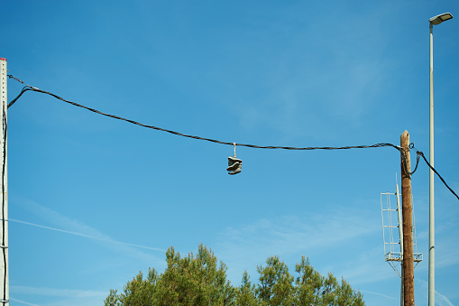 Several pairs of sports shoes hanging from electrical cables, possibly from a street gang