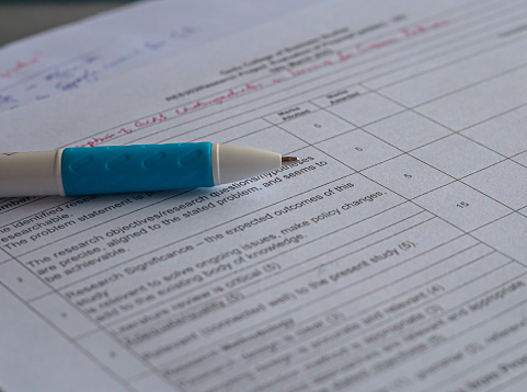 A macro (closeup) of a white pen with blue rubber on a paper with survey questions on it