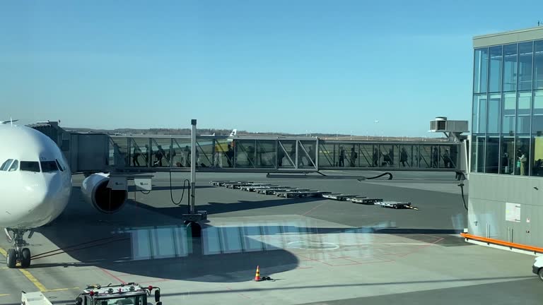 Passengers Boarding a Commercial Flight, Entering the Plane Through A Passenger Boarding Bridge (PBB) air bridge, jet bridge, jetway, and sky bridge