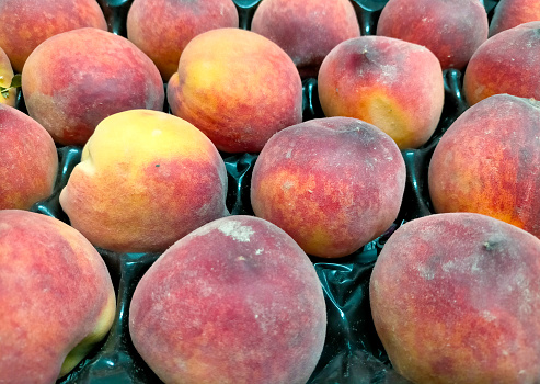 Paraguayan sweet peaches stacked in a container box to the raw for sale, overhead photo