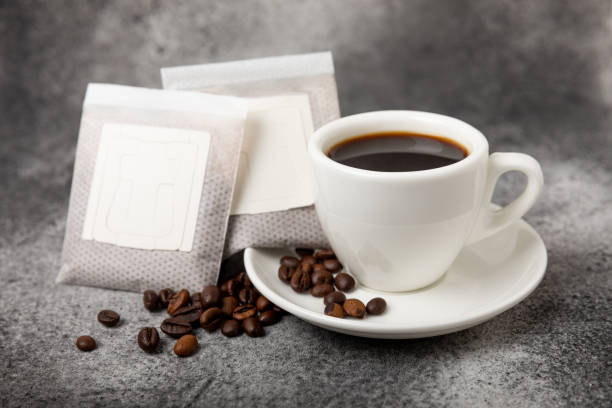 istock Drip coffee bags, coffee beans and a white cup on a texture table. Ground coffee for brewing in a cup, paper bag drip coffee filter packaging. Place to copy. Place for text. 1491697045