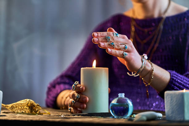 Fortune teller woman using burning candle flame for witchcraft, divination and fortune telling. Spiritual esoteric paranormal magic ritual
