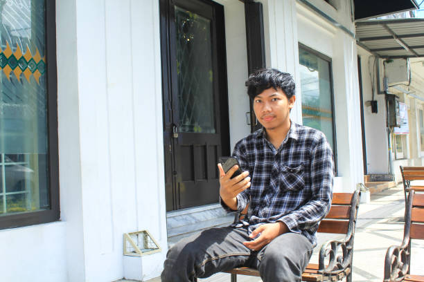 istock happy young asian man is looking to the camera while sitting, relaxing and chilling 1491699294