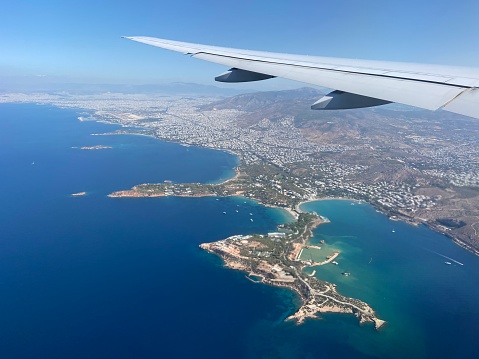 Aerial view from an airplane of an airplane wing flying above the Greek coastline and the Aegean Sea while approaching Eleftherios Venizelos Athens International Airport in Greece