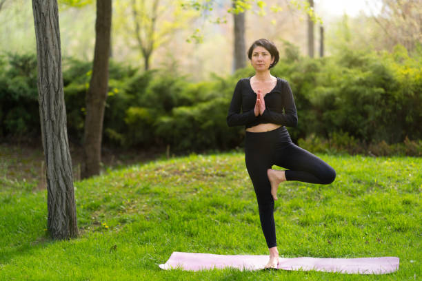 istock Mature woman doing yoga exercise with mat on grass in park 1491704280