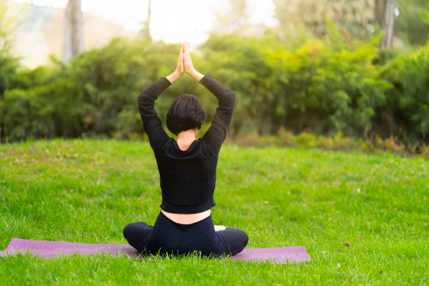 istock Mature woman doing yoga exercise with mat on grass in park 1491704841