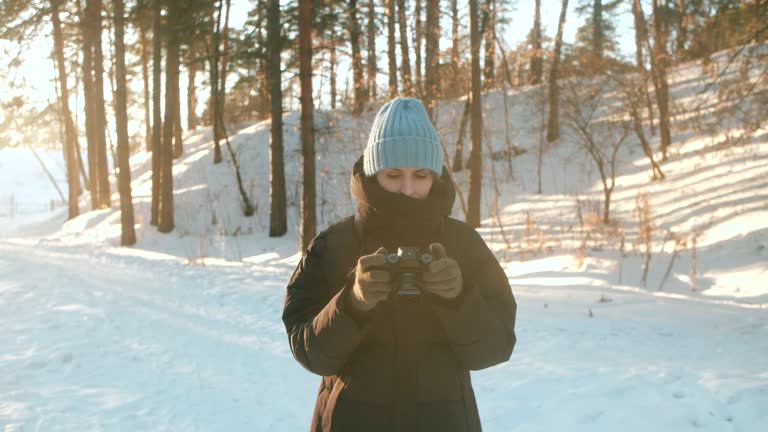 Girl shoots with camera against background of winter landscape