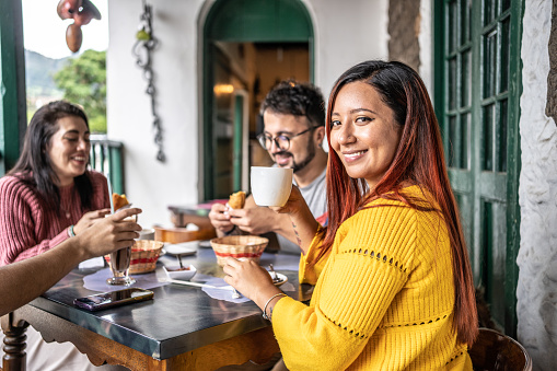 Portrait of a young woman eating with friends at a coffee shop