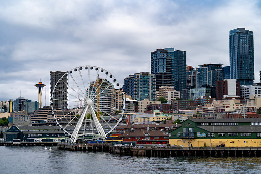 Seattle, WA - June 2022: The Seattle ferris wheel and Space Needle visible amongst the Seattle skyline from across the Puget Sound.