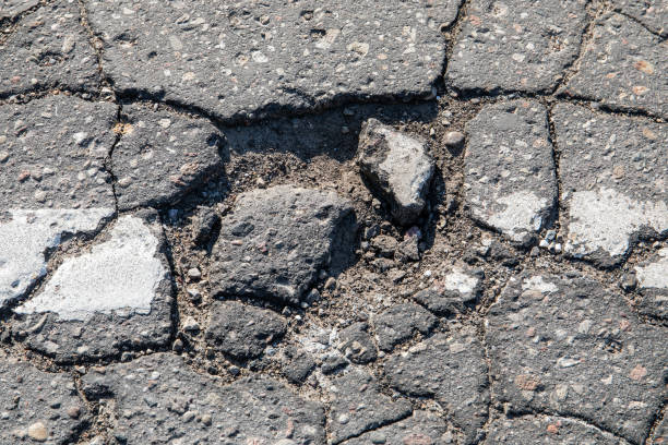 istock Damaged and potholed asphalt pavement. Danger and traffic safety 1491714321