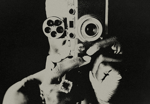 Portrait of a black female photographer. She is taking a picture with an old analog camera.