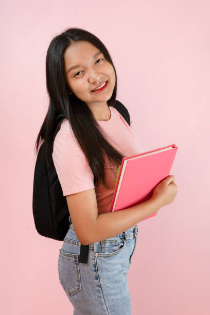 istock Student young girl with book and backpack on pink background. 1491717463
