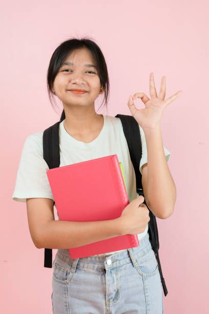 istock Happy student young girl hold pink book and backpack on pink background. 1491718085