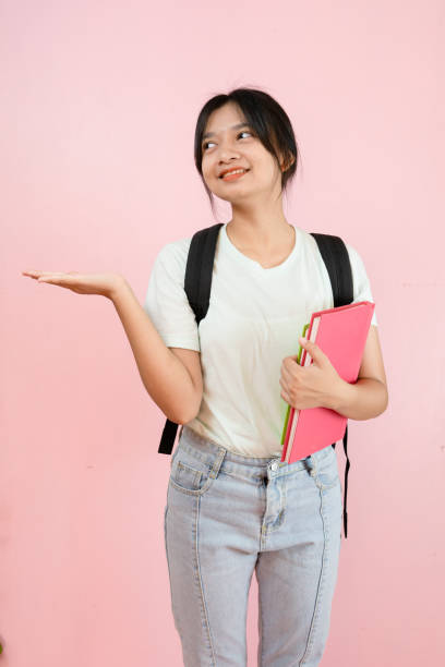 istock Happy student young girl hold pink book and backpack on pink background. 1491718100