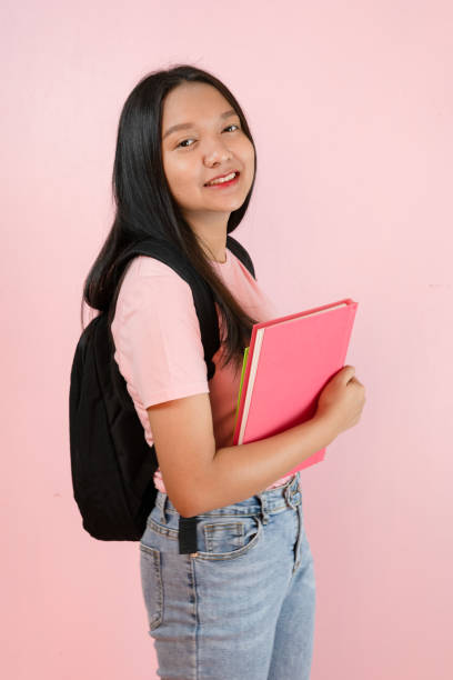 istock Student young girl with book and backpack on pink background. 1491718291