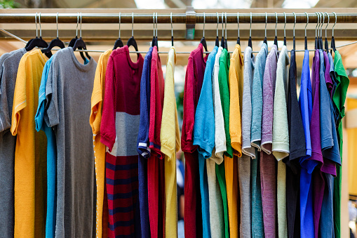 A selection of colorful t shirts on the peg in a modern clothing store.